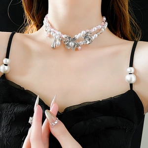 Detail of double-layer pearl choker with floral silver pendant on a black dress