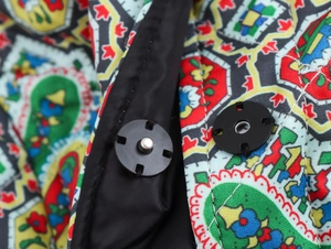 Detail of the magnetic snap closure on printed fabric with colorful geometric patterns