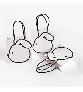 Detail of three white paper gift bags featuring minimalist black line cartoon dog patterns
