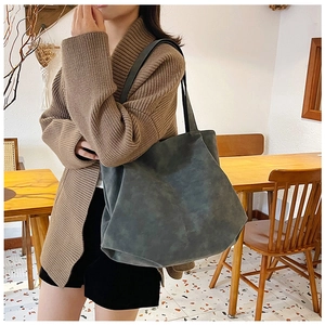 Deep green suede tote bag shown on model in a cafe setting for daily commuting