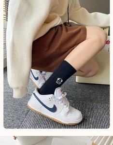 Detail of black cotton socks with white dog embroidery paired with white sneakers