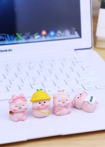 Detailed view of four cute pink resin pig figurines on a desk near a computer keyboard