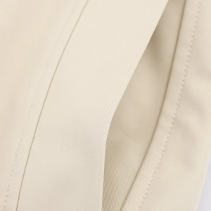 Macro shot of beige twill fabric texture and seamless stitching on women's windbreaker