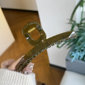 Detail of translucent olive green hair claw clip with strong gold metal spring mechanism