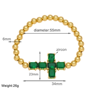 Detail view of 6mm gold beaded bracelet with 23x34mm green zircon cross pendant
