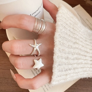 Close-up of multilayer silver star rings on hand with a cozy knit sweater background