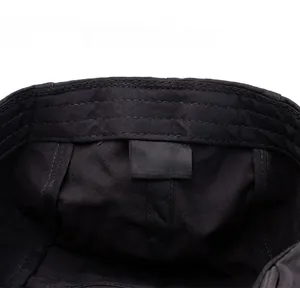 Detail of the internal care label on a black 100% cotton newsboy hat showing quality stitching