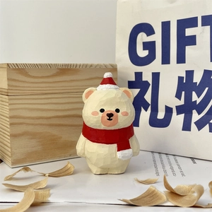 Detail of hand-carved wooden bear ornament with festive Christmas hat and scarf