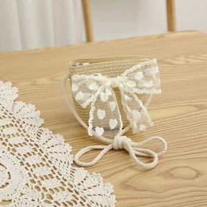 Détail du sac bandoulière en paille avec nœud en dentelle cœur blanc et bandoulière en corde