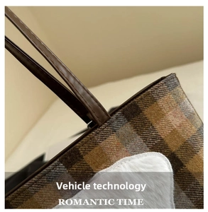 Detail of plaid tote bag showing leather handle stitching and fluffy fabric patch