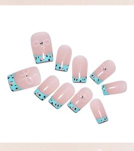 Détail de faux ongles French bleus avec motifs léopard et nœuds en cristal