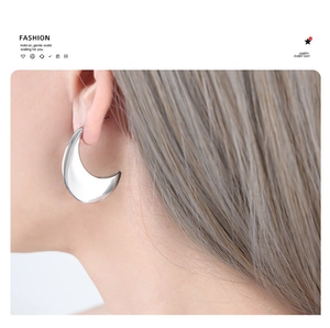 Gros plan de boucles d'oreilles minimalistes en forme de croissant argenté