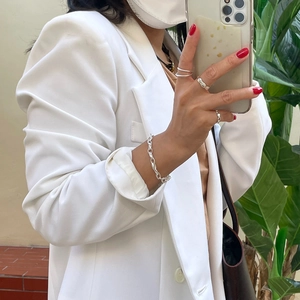 Minimalist 925 sterling silver rings and chain bracelet styled with a chic white blazer