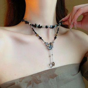Detail of layered black beaded necklace with a butterfly pendant and heart charms