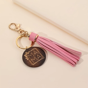 Detail of wooden MAMA charm with gold lettering, pink tassel and metal keychain ring