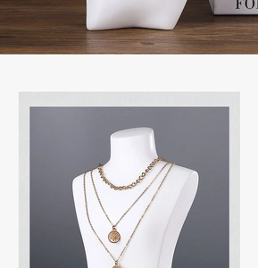 Detail of layered gold necklaces with circular pendants on resin mannequin bust