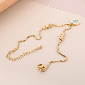 Detail of gold evil eye anklet with blue crystal pendant and lobster clasp closure