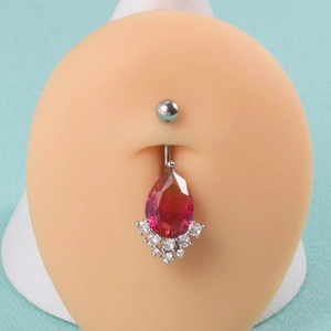 Belly button ring with red teardrop gem and clear crystals shown on a model