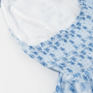 Detail of blue floral dress featuring elastic smocked bodice and layered chiffon fabric
