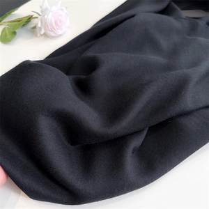 Detail of soft black linen scarf fabric texture with a decorative white rose accent
