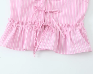 Detail view of pink striped top featuring a center drawstring tie and ruffled hem details
