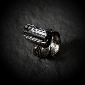 Macro shot of raw black tourmaline stone on a vintage bronze feather-shaped ring band