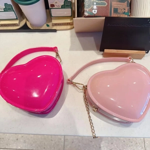 Detailed view of pink heart-shaped jelly bags with glossy finish and gold chain straps