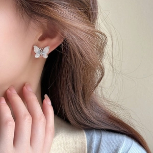 Détail macro de boucle d'oreille papillon argentée avec incrustation nacrée bleue