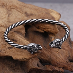 Close-up of wolf head engraving on a black and silver braided steel cuff bracelet
