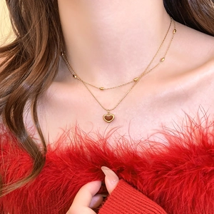 Close-up of double layer gold necklace with heart pendant and beads on neck
