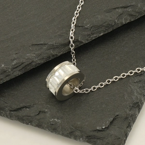 Polished stainless steel necklace with clear crystal pendant on grey slate background