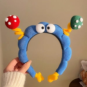 Dettaglio di un cerchietto in peluche blu con occhi a fungo e dettagli a molla gialli
