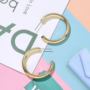 Classic golden hollow fish-shaped copper earrings on a stylish geometric backdrop