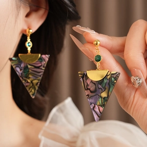 Detailed close-up of vintage golden earrings featuring green gems and resin triangle charms