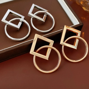 Gros plan de boucles d'oreilles géométriques or et argent sur un plateau en cuir brun