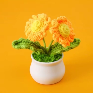 Handmade crochet daisy potted plant with orange gradient petals in a white ceramic pot