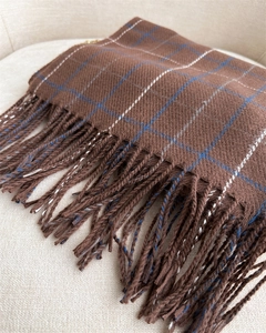 Close-up of brown plaid scarf with blue accents and soft fringe tassels texture