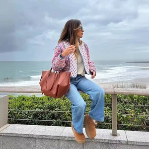 Women's reversible pink floral quilted jacket paired with leather bag and wool boots