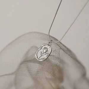 Détail macro du relief de tulipe sur un pendentif pièce irrégulier avec chaîne serpent