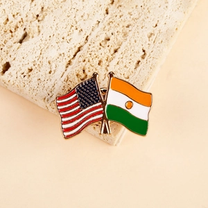 Detailed close-up of US and Niger flags crossed metal enamel pin on stone surface