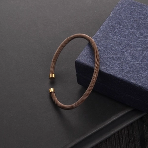 Brown mesh cable bracelet with gold tips shown next to a dark blue textured gift box