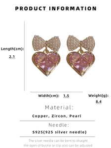 Dettaglio degli orecchini a cuore rosa con fiocco dorato e perle incastonate