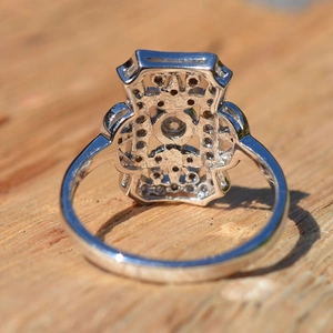 Macro detail of silver geometric hollow ring with sparkling stones on wood surface