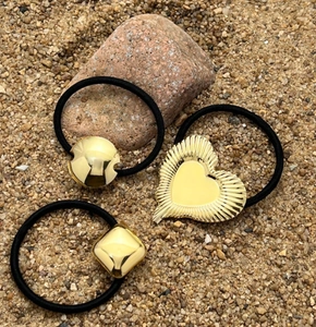 Detailed view of elastic hair ties with gold-tone heart, square, and sphere metal accents