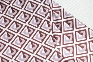 Close-up of geometric pattern fabric with brown and lavender square print and stitching
