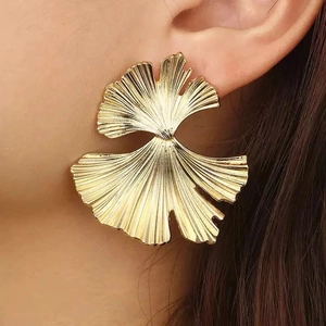 Statement gold-finished ginkgo leaf stainless steel earrings shown on model
