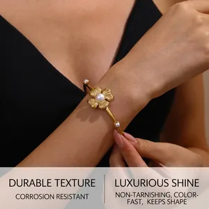 Detailed view of vintage gold flower bangle with white pearl inlay worn by a model