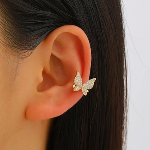 Detail of a golden butterfly ear cuff with shimmering micro-set zircons on the ear cartilage