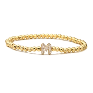 Detail of gold beaded bracelet with a micro-paved cubic zirconia letter M pendant