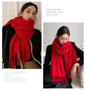Detail shot of soft red cashmere-feel scarf with fringe tassels worn by a model